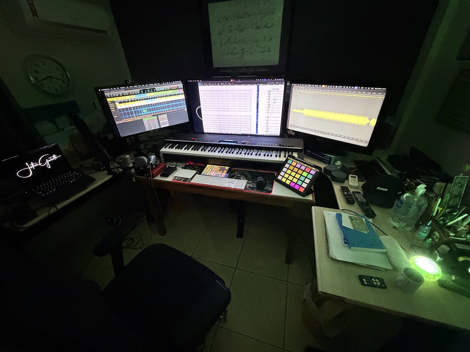 Estúdio atual de Jether Garotti, com teclado, telas de produção musical e partitura